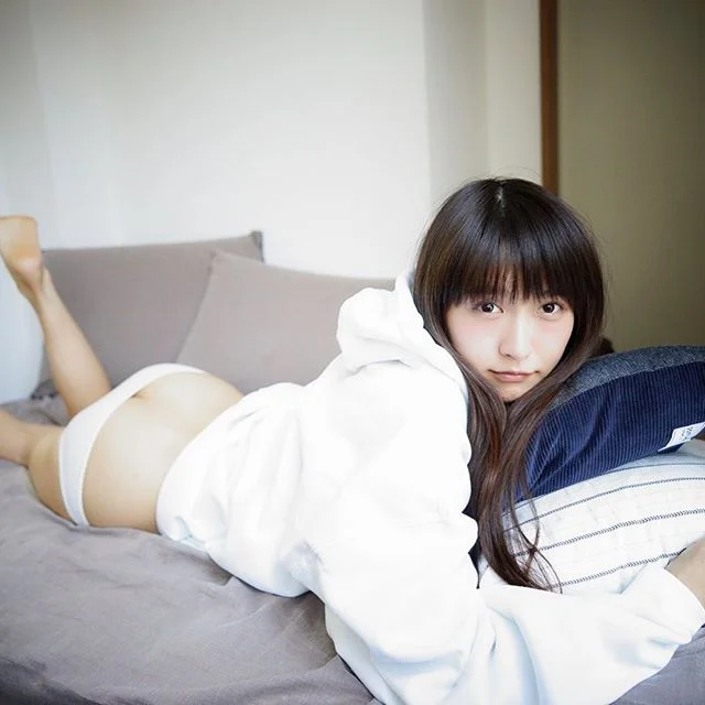女子穿着白色卫衣趴在床上看向镜头